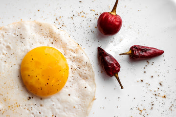 Fried egg on a white plate with dried red chili peppers