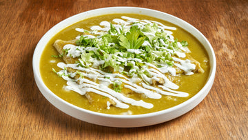 Chicken enchiladas covered in green salsa verde with crema and fresh cilantro